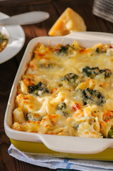 Broccoli and pumpkin mac and cheese in a ceramic dish on a wooden background. Close up.