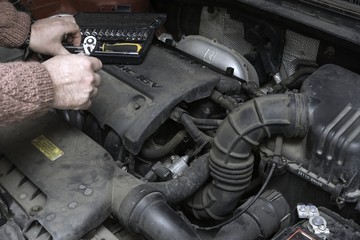 the car mechanic fixes the car engine by tools