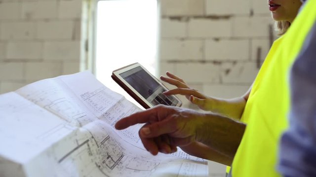 Architects and home owner with tablet at the construction site.