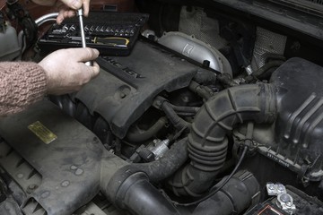 the car mechanic fixes the car engine by tools