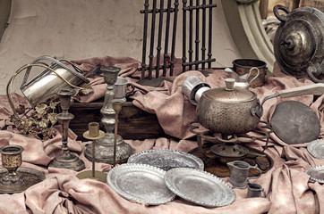 Brass containers and plates, candle holders  and other old vintage copper cookware in the flea market. Still life toned image.