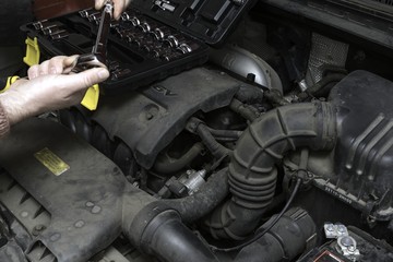 the car mechanic fixes the car engine by tools
