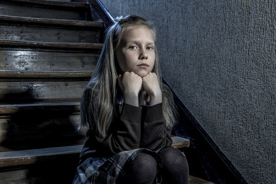 7 or 8 years old sad depressed and worried schoolgirl sitting on staircase desperate and scared suffering bullying and harassment at school