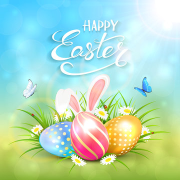 Blue sunny background with Easter eggs and rabbit ears in grass