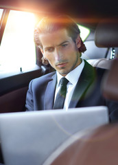 man working on laptop while sitting in the car
