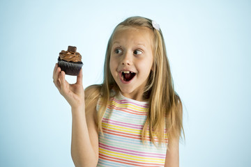 young beautiful happy and excited blond girl 8 or 9 years old holding chocolate cake on her hand looking spastic and cheerful in sugar addiction concept
