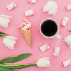 Tulips flowers with mug of coffee, marshmallows and waffle cone on pink background. Flat lay, top view.