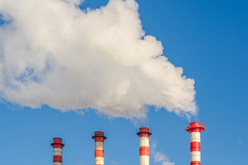 Plant pipes with smoke against clear blue sky.