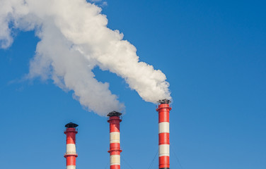 Plant pipes with smoke against clear blue sky.