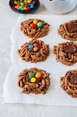Chocolate bird's nest cookies with ganache and decorated with colorful candies on a white background.