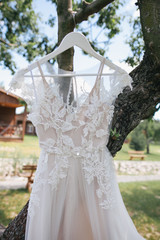 close-up view of beautiful white wedding dress hanging on tree