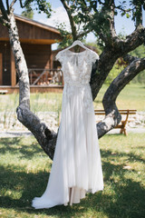 beautiful white wedding dress hanging on tree