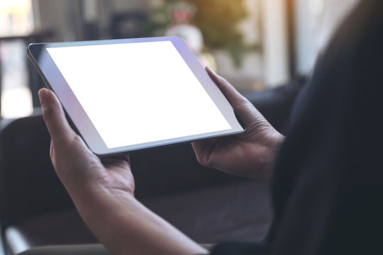 Mockup image of hands holding black tablet with blank white desktop screen