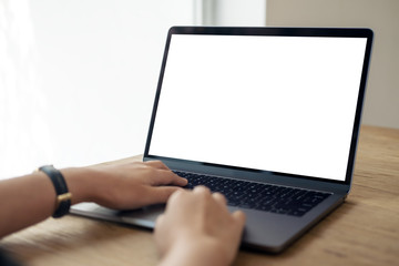 Mockup image of hands using and typing on laptop with blank white desktop screen on wooden table