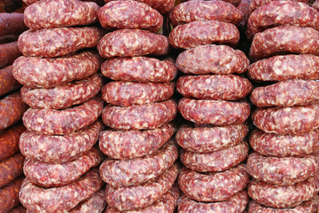 Rings of smoked pork sausage lie on the counter of a street vendor.