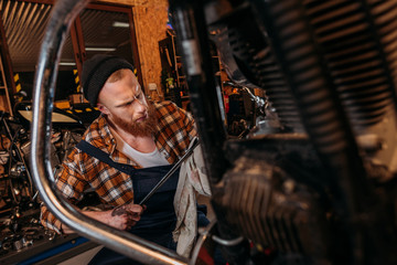 Fototapeta na wymiar concentrated bike repair station worker using wrench at garage