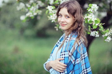 young happy woman walking in an apple orchard in the spring flowers white