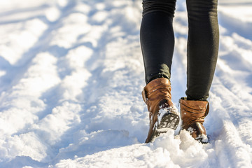 Female feet in boots and leggings, winter walking in snow