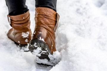 Female feet in boots in snow, winter walking