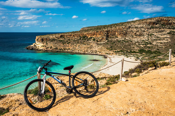 Mountain bike by the sea in Lampedusa, a small island close to Africa, part of the Pelagie islands, Sicily. The Rabbit beach in the background 