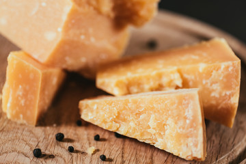 close-up view of delicious parmesan cheese with peppercorns on wooden cutting board