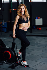 Fototapeta na wymiar athletic girl stand near a bicycle simulator