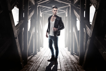 Homme sur un pont en bois avec une veste en cuir et des bottes