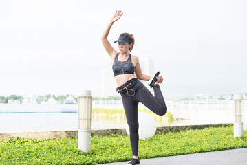 Fototapeta na wymiar asian woman doing stretching exercises outdoors along city sidewalk