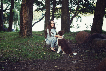 Fototapeta premium Young woman playing with collie dog outdoors in the park.