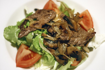 Leaves of green salad, meat and fried onions