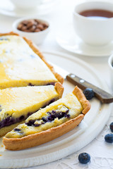 Tea time. Homemade blueberryy cheesecake, cups of tea, nuts and berry on white table cloth