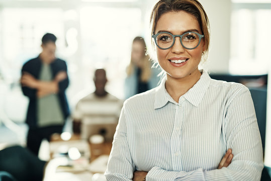 Smiling young businesswoman with colleagues working in the background
