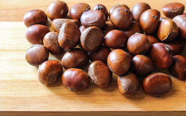 Fresh chestnuts on dark black rustic background. Pile of fresh chestnuts ready to roast shot over black antique background. Top view.