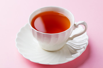 Tea in white cup on pink background. Close up.