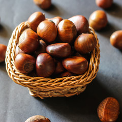 Fresh chestnuts on dark black rustic background. Pile of fresh chestnuts ready to roast shot over black antique background. Top view.