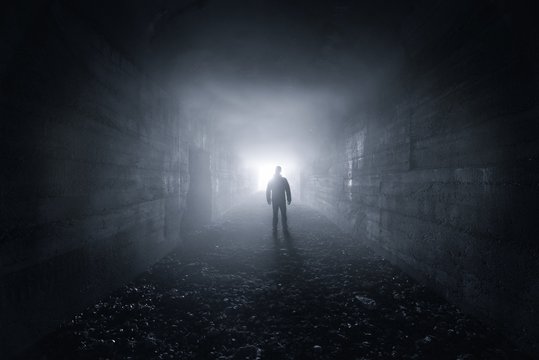 Fototapeta mężczyzna w ciemnym betonowym tunelu wychodzi z wyjścia - koncepcja samotności