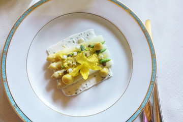 Top view of delicious white asparagus with mimosa egg and goat cheese for starter