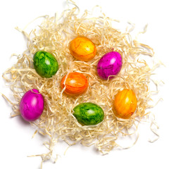 Fototapeta na wymiar Colored eggs on packing straw. Isolated. Easter 2018. Top view