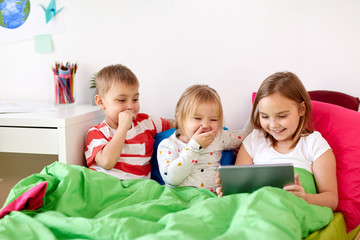 little kids with tablet pc in bed at home