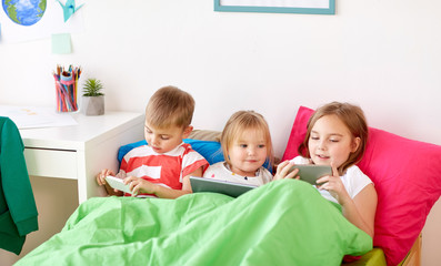kids with tablet pc and smartphones in bed at home