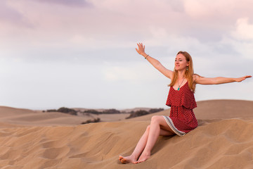 Fototapeta na wymiar Glückliche Frau sitz auf dem Sand in Maspalomas 