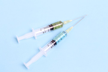 Syringe closeup with blue serum isolated on blue background.