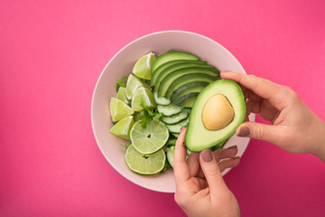 a woman holds a plate with a dietal avocado salad