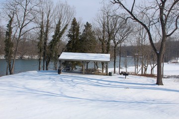 Fototapeta na wymiar The empty picnic shelter in the parks snowy landscape.