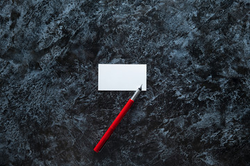 few clean white business cards with space for text and a red fountain pen on a dark marble surface