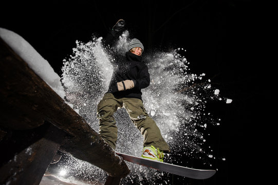 Active female snowboarder riding down the mountain slope at night