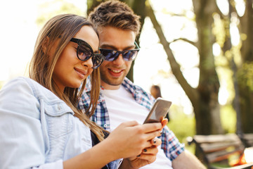 Young couple having fun with a smartphone in the park
