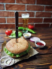  гамбургер проткнутый ножом на газете с пивом