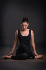 Fototapeta na wymiar Young calm beautiful woman of the brunette with long hair wearing black sportswear in yoga pose