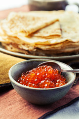 Red salmon caviar with pancakes on the background